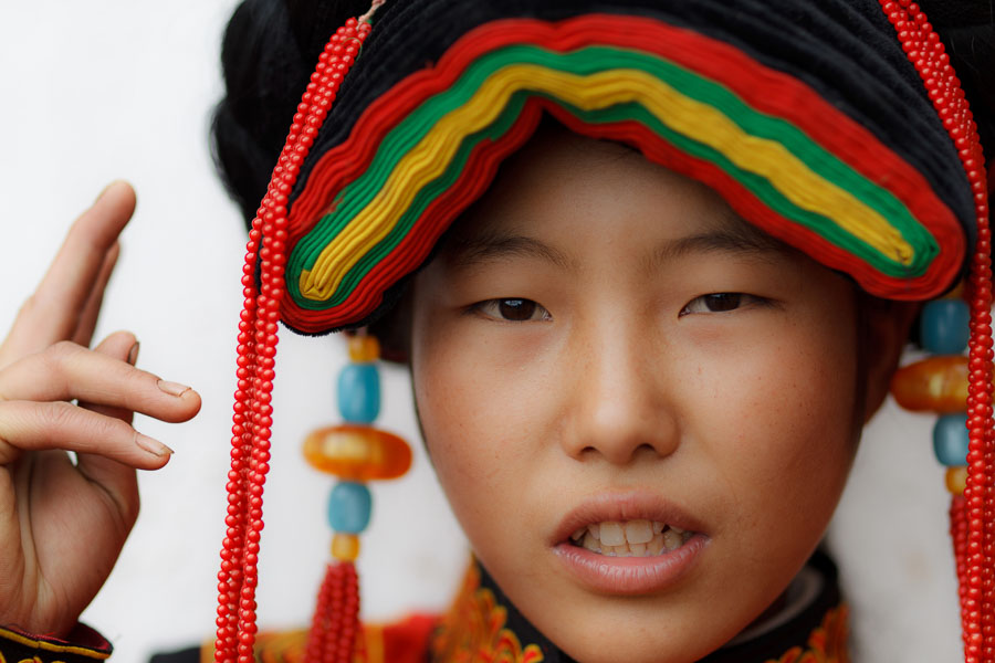 A young Yi girl in China shows a hand gesture meaning beautiful.